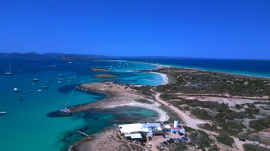 İspanya 'nın Formentera kentindeki bir sahil barının yakınındaki turkuaz sularda demirleyen yelkenliler nefes kesici bir hava perspektifi sunuyorlar. Yukarıdan insansız hava aracı görüntüleri 