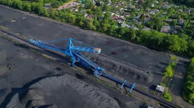 Kömür kazıcısını yerleşim alanı yakınlarındaki bir kömür terminalinde geri alan yayıcı. İHA kamerası aşağıya bakıyor 