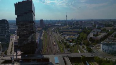 Güneşli bir günde Amazon merkez kulesi, demiryolu hatları ve modern mimarisi olan Berlin şehir manzarası. Ters İHA uçuşu 