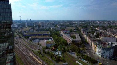 Güneşli bir günde Amazon merkez kulesi, demiryolu hatları ve modern mimarisi olan Berlin şehir manzarası. Ters İHA uçuşu 
