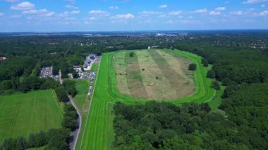 Almanya 'da bir ormanın yakınındaki at yarışı pistinin havadan görünüşü, park yeri görünür. İHA 'yı çek 