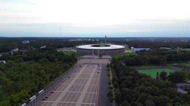 Günbatımında Olympiastadion Berlin 'in havadan görünüşü çan kulesini, park alanlarını ve şehrin ufuk çizgisini gösteriyor. panorama yörünge dronu 