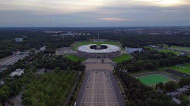 Günbatımında Olympiastadion Berlin 'in havadan görünüşü çan kulesini, park alanlarını ve şehrin ufuk çizgisini gösteriyor. Yukarıdan drone atışı 