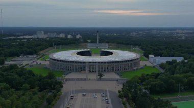 Günbatımında Olympiastadion Berlin 'in havadan görünüşü çan kulesini, park alanlarını ve şehrin ufuk çizgisini gösteriyor. panorama yörünge dronu 