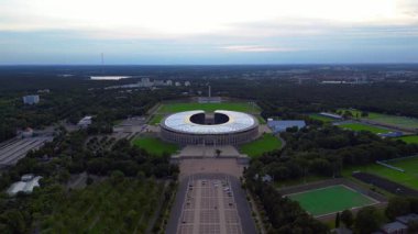 Günbatımında Olympiastadion Berlin 'in havadan görünüşü çan kulesini, park alanlarını ve şehrin ufuk çizgisini gösteriyor. İHA yükseliyor 