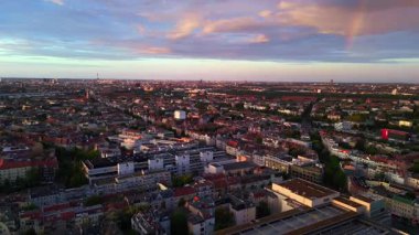 Altın saat boyunca binaların üzerinde gökkuşağı görünen Berlin şehir manzarası. Ters İHA uçuşu 