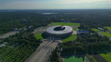 Güneşli yaz gününde Olympiastadion Berlin 'in hava manzarası çevredeki ağaçları ve otoparkı gösteriyor. panorama genel görünüm dronu 