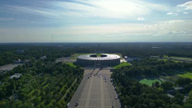 Güneşli yaz gününde Olympiastadion Berlin 'in hava manzarası çevredeki ağaçları ve otoparkı gösteriyor. panorama genel görünüm dronu 