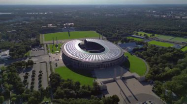 Güneşli yaz gününde Olympiastadion Berlin 'in hava manzarası çevredeki ağaçları ve otoparkı gösteriyor. statik üç ayaklı insansız hava aracı 