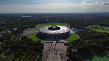 Güneşli yaz gününde Olympiastadion Berlin 'in hava manzarası çevredeki ağaçları ve otoparkı gösteriyor. statik üç ayaklı insansız hava aracı 
