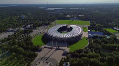 Güneşli yaz gününde Olympiastadion Berlin 'in hava manzarası çevredeki ağaçları ve otoparkı gösteriyor. İHA kamerası aşağıya bakıyor 