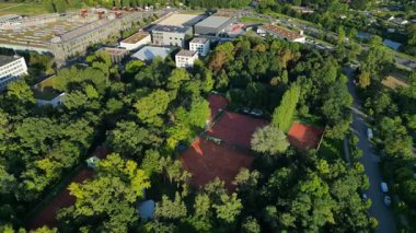 Yoğun bir ormanın içine yerleştirilmiş çok sayıda tenis kortunun havadan görünüşü şehrin kalbine huzurlu bir kaçış sağlıyor. Drone görüntülerini daire içine al 