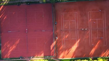 Güneşli bir günde kil kortlarda tenis oynayan insanların hava görüntüsü. dikey kuşların gözünden drone kameralar aşağıya bakıyor. hız rampası hiper hareket hızlandırılmış dönüş zamanı sağ drona 