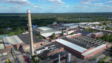 Hennigsdorf çelik endüstrisinin hava manzarası. Endüstriyel binalar, bacalar, depolama alanı ve arka planda bir nehir. Yukarıdan drone atışı 
