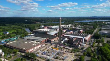 Hennigsdorf sanayi bölgesinin modern ofisleri, eski fabrika binaları ve mavi gökyüzünün altındaki bacaları. İHA alçalıyor 