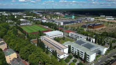 Hennigsdorf Lisesi 'nin havadan görünüşü modern mimarisini, spor tesislerini, park alanını, kentsel manzarasını gözler önüne seriyor. Hız rampası hiper hareket zamanı hızlandırılmış panorama yörünge dronu 