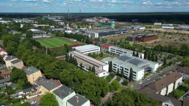 Hennigsdorf Lisesi 'nin havadan görünüşü modern mimarisini, spor tesislerini, park alanını, kentsel manzarasını gözler önüne seriyor. Ters İHA uçuşu 