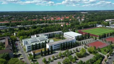 Hennigsdorf Lisesi 'nin havadan görünüşü modern mimarisini, spor tesislerini, park alanını, kentsel manzarasını gözler önüne seriyor. panorama genel görünüm dronu 