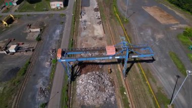 Gantry Turnası, güneşli bir yaz gününde Hennigsdorf çelik fabrikalarında hurda metal taşıyor. Yukarıdan drone atışı 