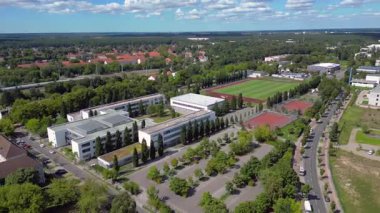 Hennigsdorf Lisesi 'ndeki spor tesisleri arasında futbol sahası, koşu pisti ve yerleşim alanlarındaki diğer binalar da var. Hız rampası hiper hareket zamanı hızlandırılmış panorama yörünge dronu 