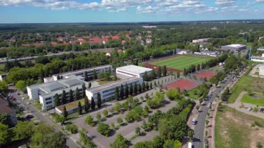 Hennigsdorf Lisesi 'ndeki spor tesisleri arasında futbol sahası, koşu pisti ve yerleşim alanlarındaki diğer binalar da var. Yukarıdan drone atışı 