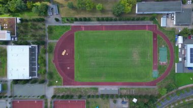 Hennigsdorf Lisesi 'ndeki spor tesisleri arasında futbol sahası, koşu pisti ve yerleşim alanlarındaki diğer binalar da var. Üstten kumandalı hava aracı kameraları aşağıya bakıyor. 