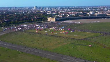 Almanya, Berlin 'deki Tempelhofer Feld dev uçurtma festivalinde büyük bir kalabalık toplandı. panorama genel görünüm dronu 