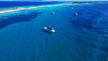 Kristal berrak turkuaz sularda yüzen sayısız yat ve tekneli kıyı şeridi. İHA 'nın üzerinden ters uçuş yap 