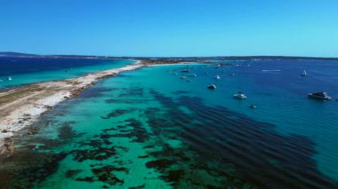 Kristal berrak turkuaz sularda yüzen sayısız yat ve tekneli kıyı şeridi. Ters İHA uçuşu 