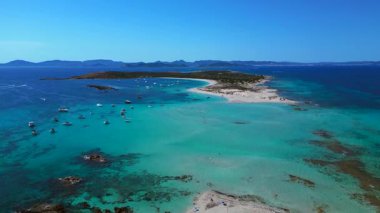 Beyaz kumlu plajları, turkuaz suları ve demirli tekneleri olan Espalmador adası. Arkadaki Ibiza ve Es Vedra adası. İHA alçalıyor 