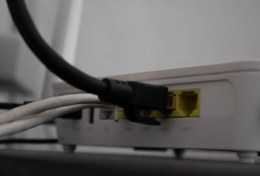 Siyah ethernet kablosu, beyaz bir wifi yönlendiricisine bağlı.
