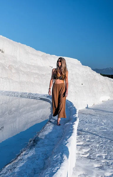 Sarışın kadın Pamukkale Türkiye 'deki Doğal Travertin havuz ve teraslarında yürüyor