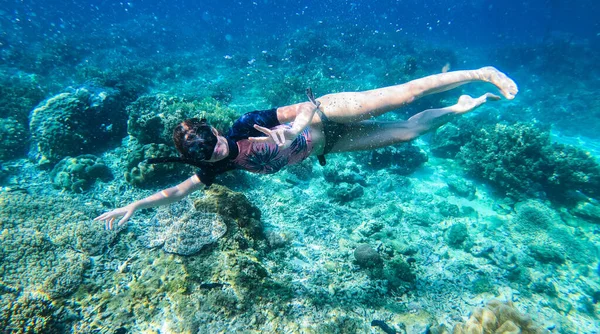 Happy woman with snorkeling mask and dive underwater in coral reef. Travel activity, water sports, outdoor adventure