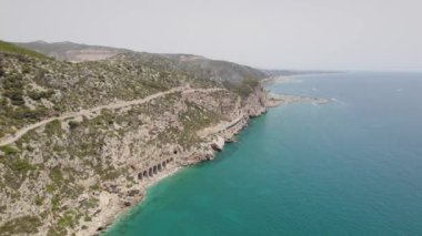 4k Aerial view of the road and train line along the coastline with mountains and blue sea. Garraf, Spain