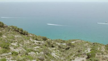 4k Aerial view of mountain and road with traffic along the coastline. Boats in the sea.