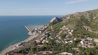 Drone view of Garraf, Spain, on green mountains and blue sea on clear horizon. Harbour and highway with tunnel 