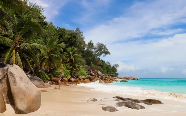 Standing woman in Seychelles looking at the waves in the beach tropical forest