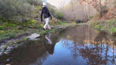 Woman walking in the fall forest plenty of leaves on autumn day near the river