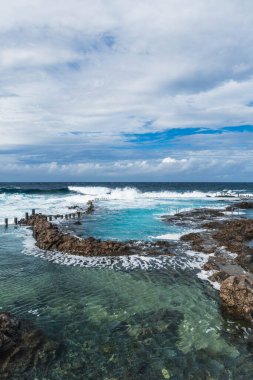 Denizin önündeki doğal tuzlu su havuzu. Las Palmas de Gran Canaria 'da cesur dalgalar