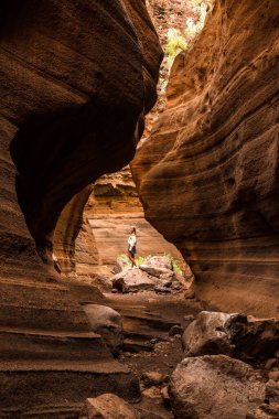 Blonde caucasian tourist woman exploring inside the canyon of Barranco de las Vacas in Gran Canaria