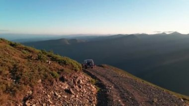4k. Aerial view of 4x4 car driving through mountain road in sundown footage
