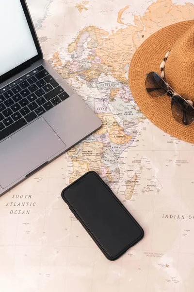 Smartphone Weltkartenschreibtisch Mit Schalter Auf Laptop Hut Und Sonnenbrille — Stockfoto