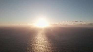 Sakin denizde günbatımının 4k videosu ve bulutların arasından geçen güneş. Suyun üzerindeki sakin manzara ve ufuk.