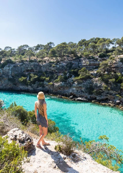 Kaliforniya pi, Mallorca ve Balear Adaları 'nda uzun sarı saçlı bir kadın. Turkuaz su kayalarla çevrili.