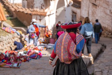 Köyde geleneksel renkli kıyafetlerini giymiş Perulu yerli bir kadının arka görüntüsü. Andean, Peru kültürü. Boşluğu kopyala. 