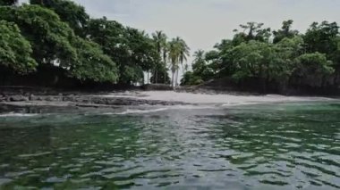 4K video, İHA görüntüsü geriye doğru uçuyor. Cennet 'teki vahşi tropikal palmiye ağaçlarının plajında şapkası olan erkek pilotsuz uçak. Panama 'da seyahat tatili. Dalgalar ve kumsallar