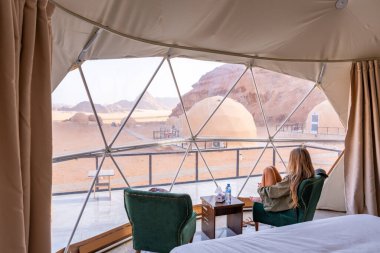 Tourist woman with long blonde hair in bubble tent at Wadi Rum protected area desert Jordan clipart