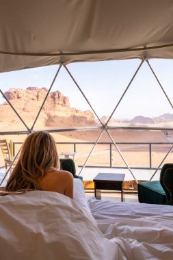 Uzun sarı saçlı çıplak turist kadın, Ürdün 'de Wadi Rum' da korunan çölü kabarcık çadırına girdi.