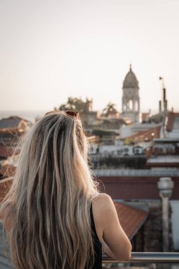 Sarışın bir kadının terastan şehrin eski şehrini dikizlemesi.