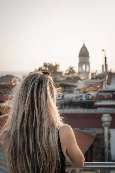Sarışın bir kadının terastan şehrin eski şehrini dikizlemesi.